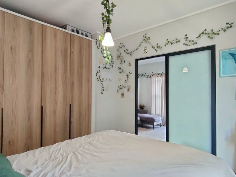 A well-maintained bedroom featuring modern wood-finish built-in wardrobes and a sleek sliding door leading to an adjacent space.