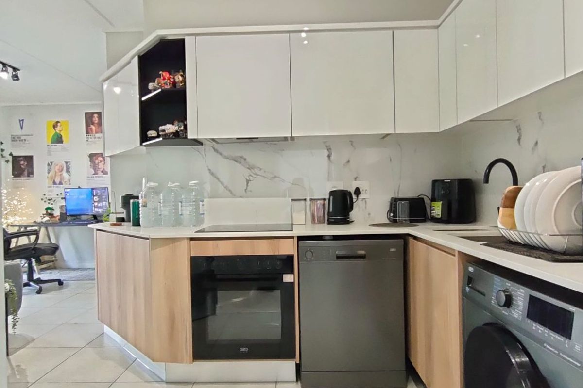 Modern kitchen featuring white gloss cabinetry, wood-tone lower units, marble-look splashback, and integrated appliances with tiled flooring.