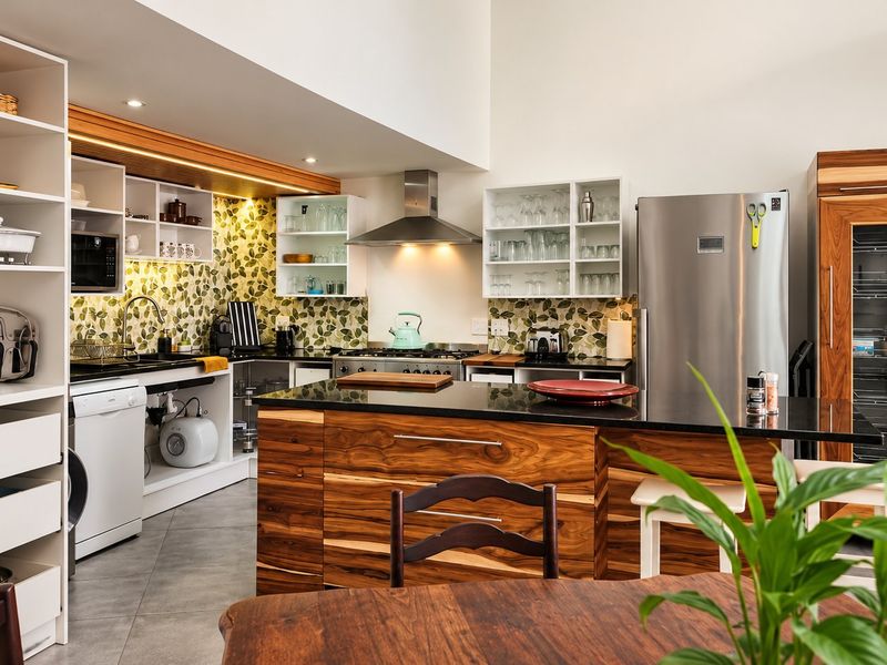 Modern kitchen featuring a central island with stone countertops, custom wood cabinetry, built-in wine fridge, and high-quality stainless steel appliances.