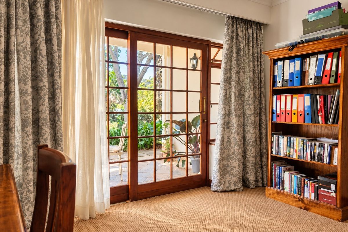 A bright living area featuring wooden sliding glass doors that provide direct access to an outdoor patio and garden space.