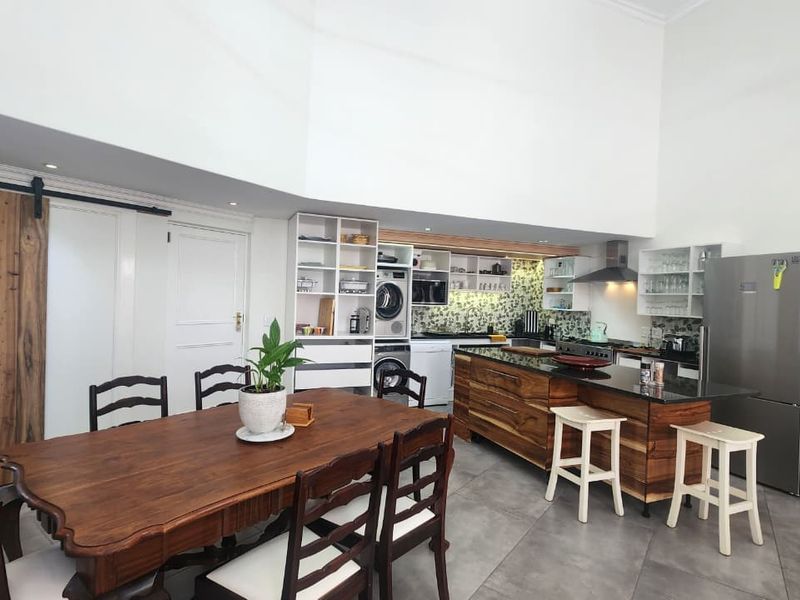 Spacious open-plan kitchen and dining area featuring custom wood cabinetry, a large kitchen island with stone countertops, and high ceilings.