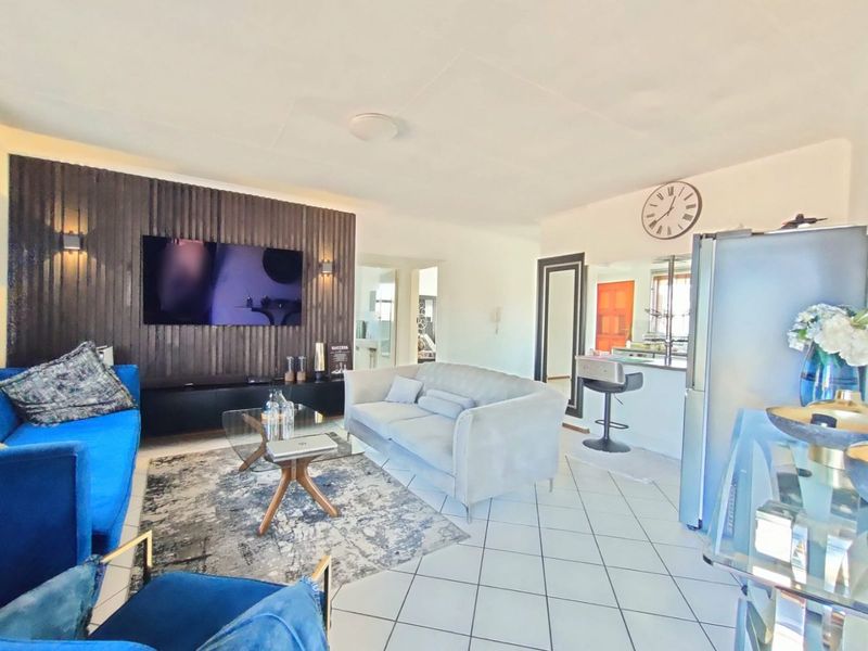 Open-plan living area featuring a modern slatted timber feature wall, tiled flooring, and a breakfast bar connecting to the kitchen space.
