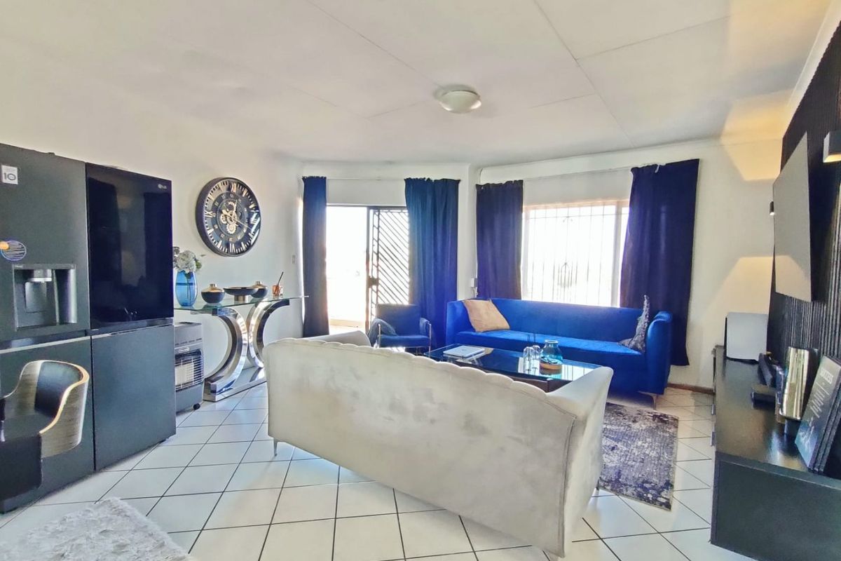Spacious living room featuring tiled flooring, large windows with security bars, and a sliding door providing access to the exterior.