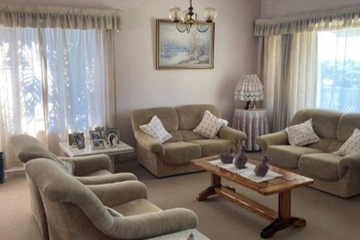 A spacious living room featuring neutral carpeting, ceiling coving, and large sliding glass doors that provide ample natural light.