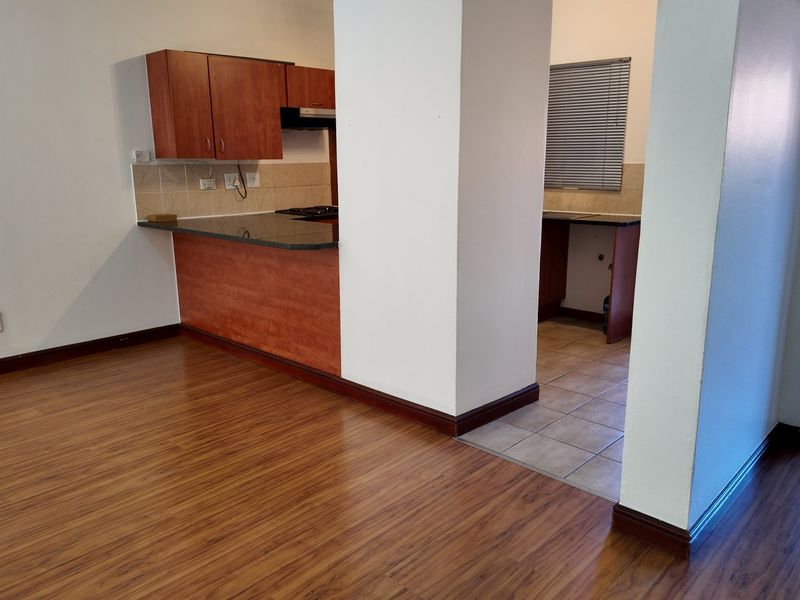 Open-plan living area featuring laminate flooring and a functional kitchen with built-in cabinetry, granite countertops, and a tiled backsplash.