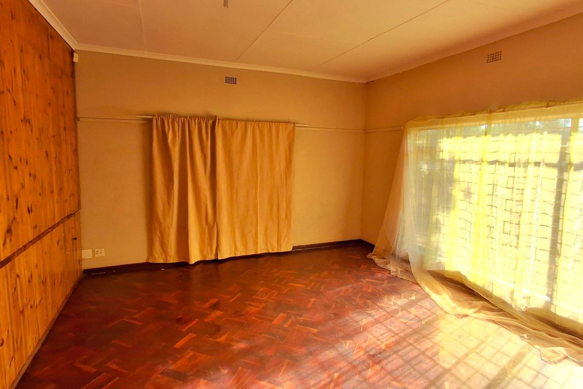 Spacious bedroom featuring original parquet flooring and extensive built-in wooden cabinetry, offering a blank canvas for renovation and modernization.