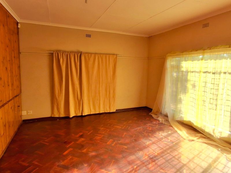 Spacious bedroom featuring original parquet flooring and extensive built-in wooden cabinetry, offering a blank canvas for renovation and modernization.
