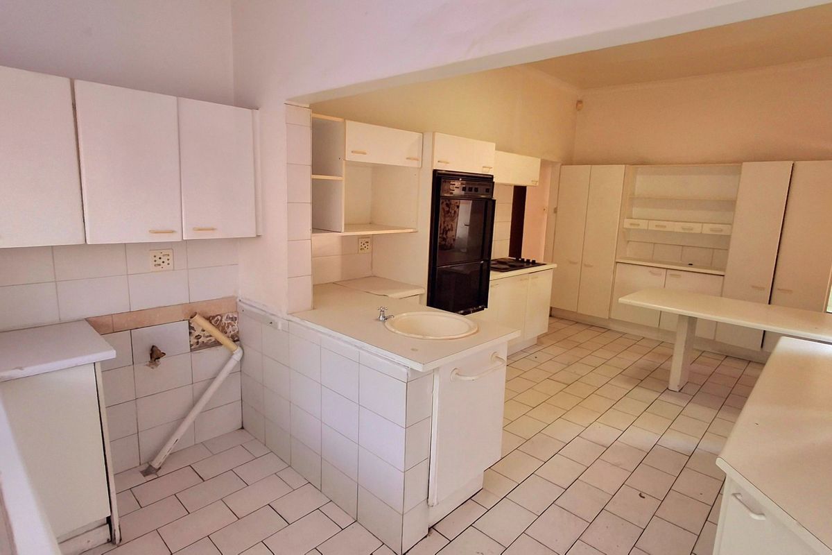 Spacious kitchen featuring extensive built-in cabinetry, tiled flooring, and integrated appliances, offering a functional layout ready for modern renovation and cosmetic updates.
