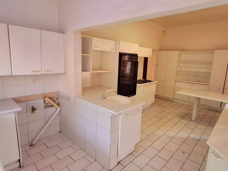 Spacious kitchen featuring extensive built-in cabinetry, tiled flooring, and integrated appliances, offering a functional layout ready for modern renovation and cosmetic updates.