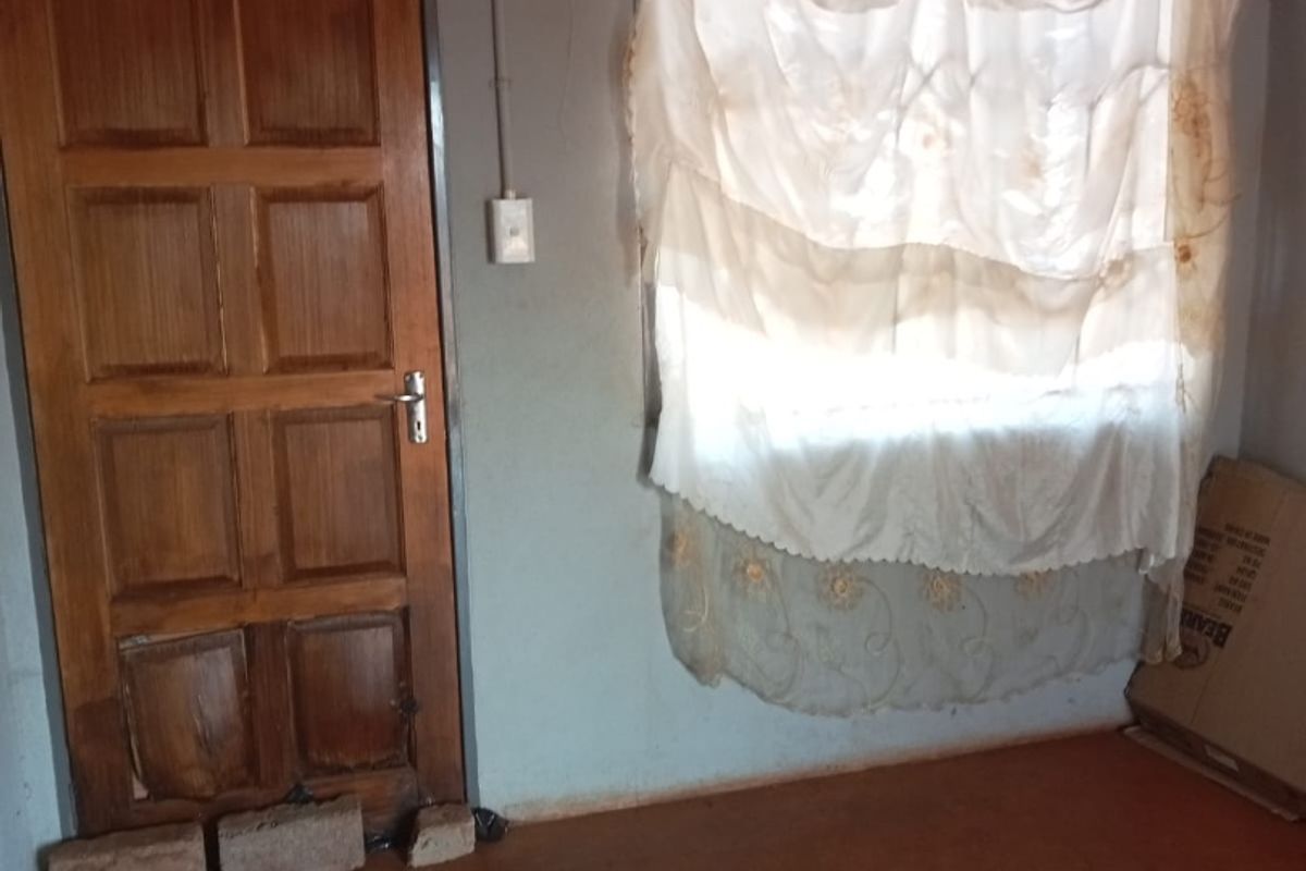 A vacant bedroom featuring a timber door and basic wall finishes, requiring cosmetic updates and repairs to the wall and flooring.