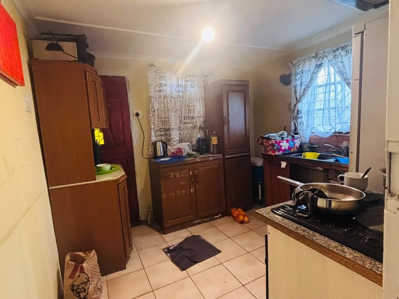 A dated kitchen featuring original cabinetry, laminate countertops, and ceramic floor tiles, offering significant potential for a modern renovation and layout update.