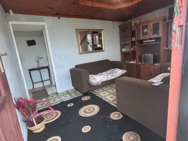 A living room featuring a timber ceiling, built-in cabinetry, and tiled flooring, currently requiring cosmetic updates to improve its overall condition and appeal.