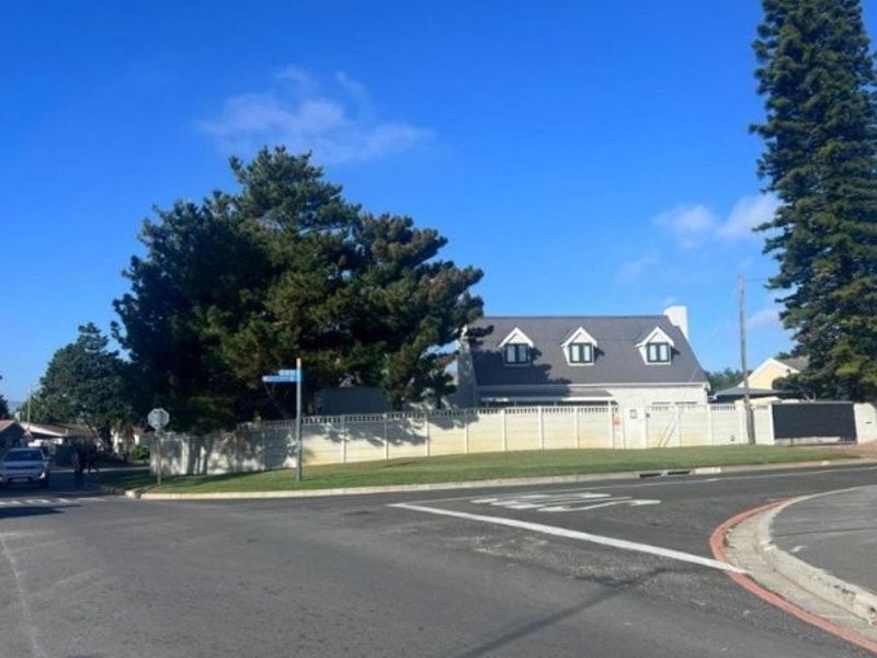 Street view of a residential property featuring a perimeter fence, pitched roof, and dormer windows, situated on a corner lot.