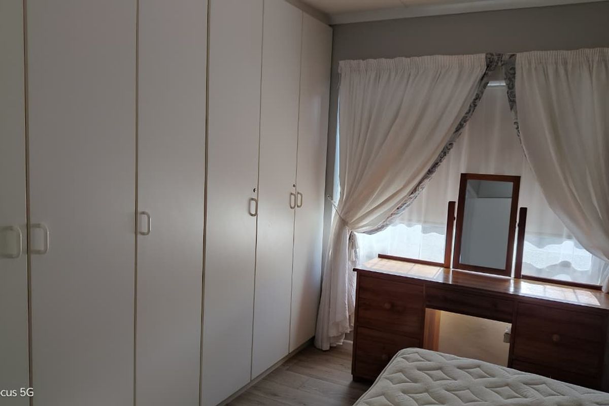 A bedroom featuring extensive floor-to-ceiling built-in cupboards and laminate flooring, providing ample storage space and a neutral foundation.