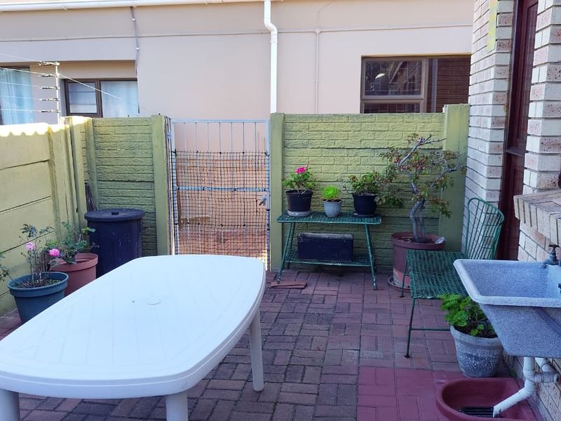 A paved rear patio area featuring a built-in utility sink and enclosed by a painted precast concrete boundary wall.