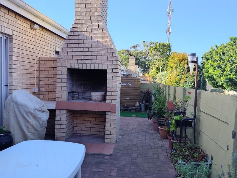 Outdoor patio area featuring a built-in brick braai, paved flooring, and direct access to the interior via a sliding glass door.