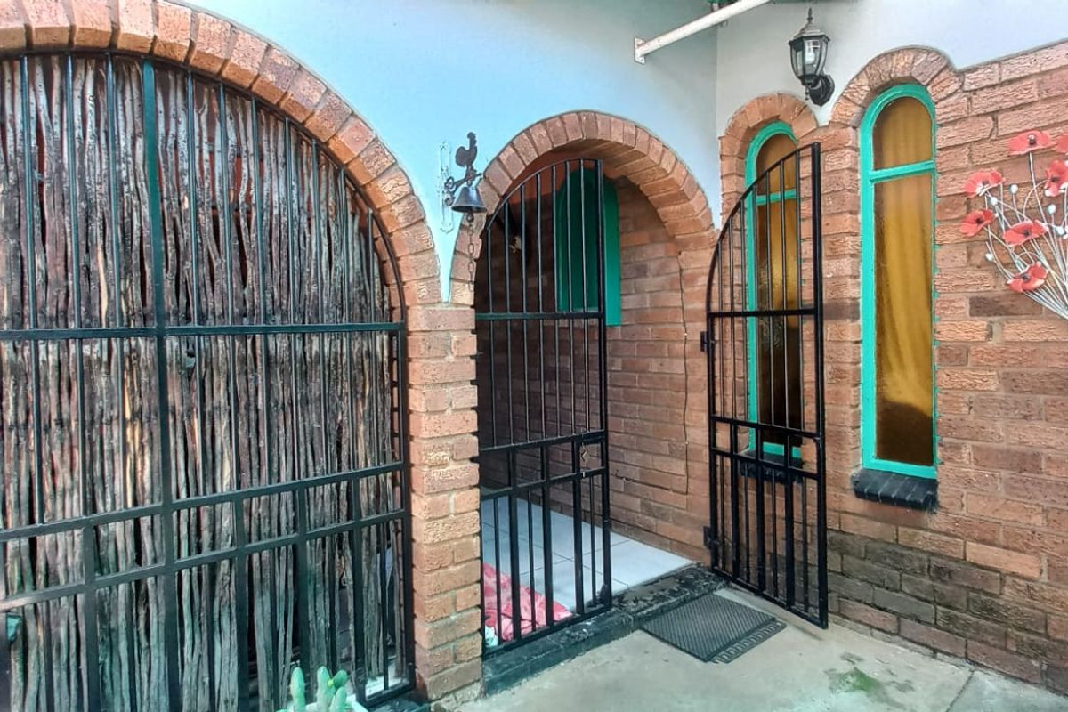 A covered rear patio area featuring distinctive brick archways, security gates, and tiled flooring, providing a sheltered outdoor transition space.