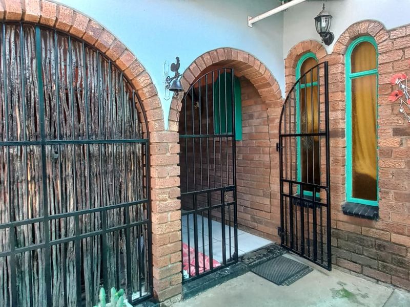 A covered rear patio area featuring distinctive brick archways, security gates, and tiled flooring, providing a sheltered outdoor transition space.