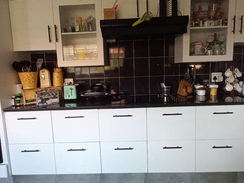 A functional kitchen featuring white cabinetry, black granite countertops, a tiled backsplash, and integrated appliances including an oven and microwave.