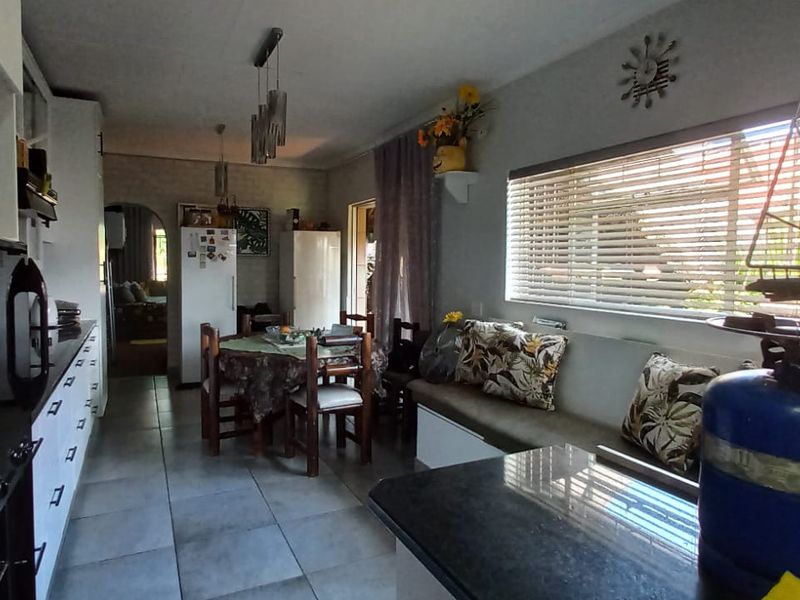 A functional kitchen featuring built-in cabinetry, integrated oven and microwave, tiled flooring, and a built-in bench seating area with venetian blinds.