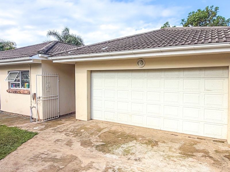Front exterior view of the property featuring a tiled roof, a white sectional garage door, and a paved driveway with security features.