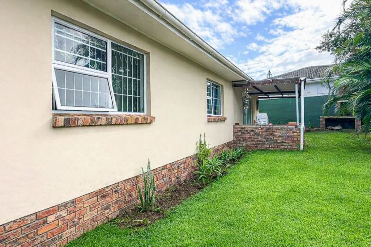 Rear exterior view of the house featuring a brick plinth, security-fitted windows, and a covered patio area with a built-in brick braai.