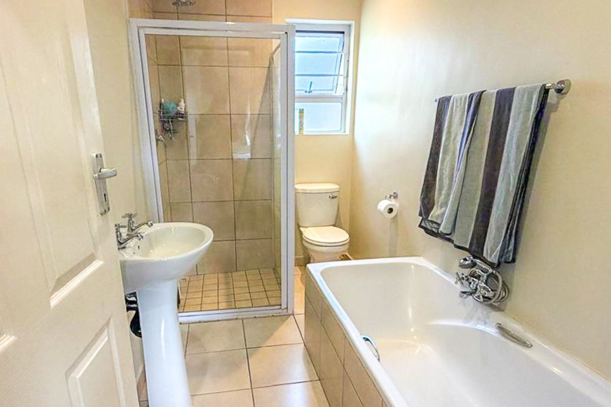 A functional bathroom featuring a pedestal basin, a separate shower enclosure with tiled walls, a toilet, and a bathtub with tiled surround.