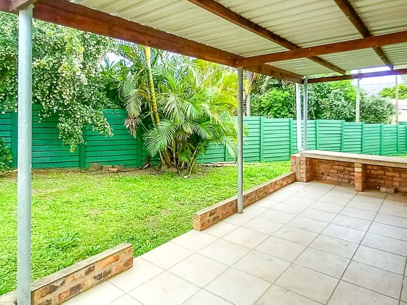 Covered outdoor patio featuring tiled flooring, a built-in brick counter, and direct access to the garden area.