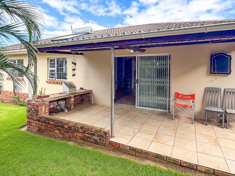 Covered patio area featuring a built-in brick counter, tiled flooring, and direct access to the interior through a sliding glass door.
