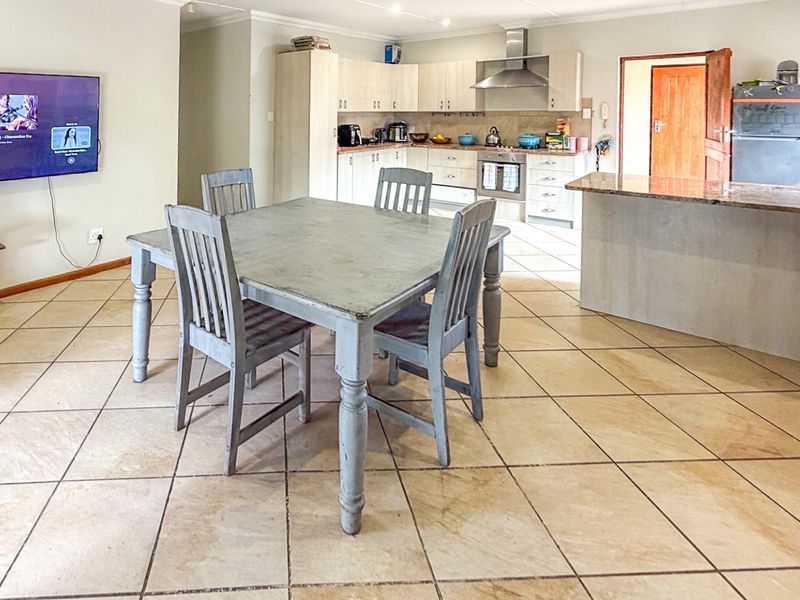 Open-plan living and kitchen area featuring tiled flooring, a central kitchen island with granite countertops, and built-in cabinetry with integrated appliances.