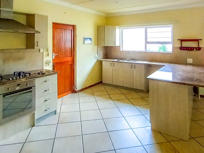Spacious kitchen featuring built-in cabinetry, stone countertops, integrated oven, gas hob, and stainless steel extractor fan with tiled flooring throughout.