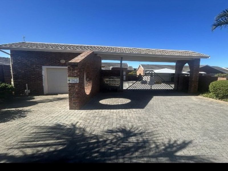 Front exterior view of the property featuring a brick facade, tiled roof, paved driveway, and a secure gated entrance with an integrated garage.