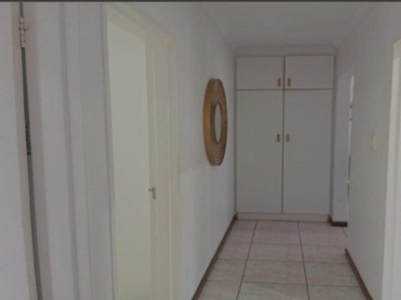 A functional hallway featuring tiled flooring and built-in storage cupboards, providing access to multiple rooms within the home.