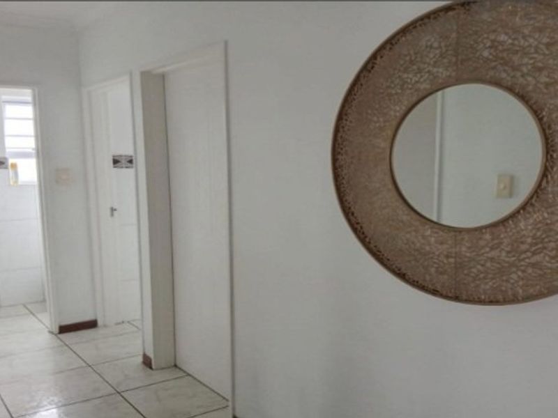 A neutral hallway featuring tiled flooring and access to multiple internal rooms.