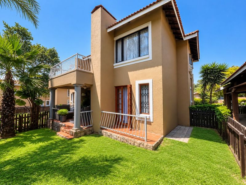 Rear view of the apartment featuring a private garden, a ground-floor tiled patio, and an upper-level balcony with metal railings.