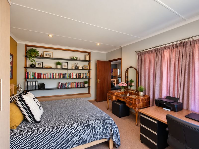 A well-maintained bedroom featuring built-in shelving, recessed downlighting, and neutral carpet flooring, offering a comfortable and functional living space.