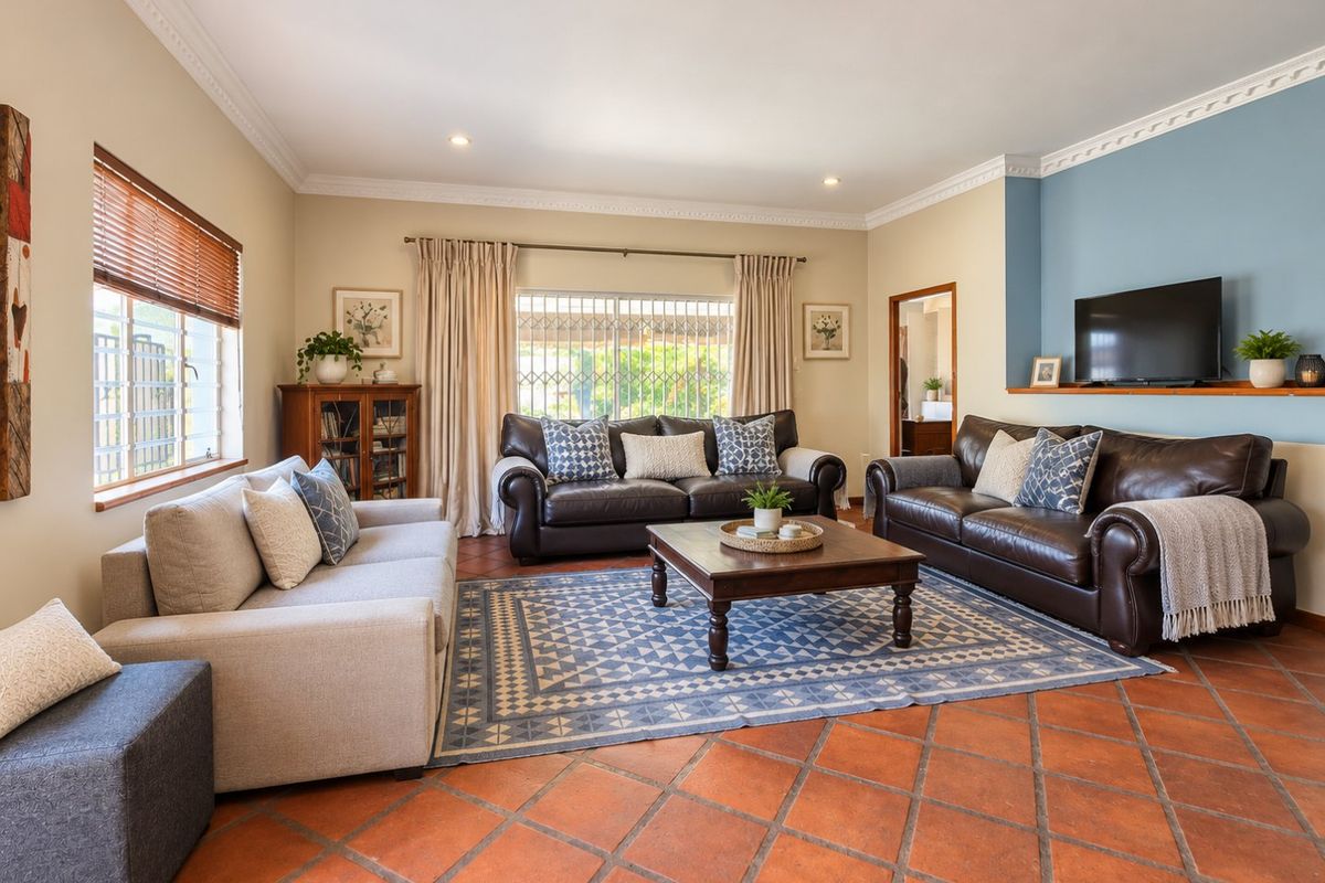 Spacious living room featuring terracotta tile flooring, crown molding, recessed lighting, and a blue accent wall with a built-in display shelf.