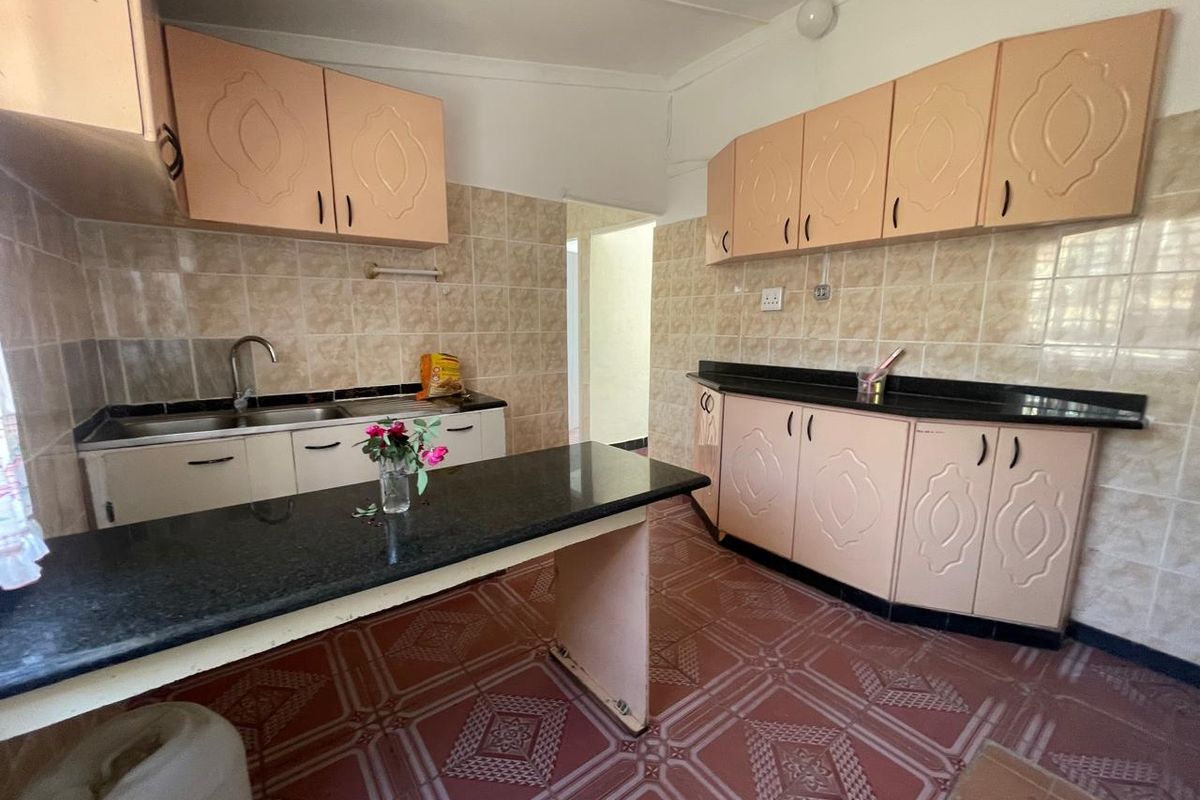 A functional kitchen featuring granite countertops, ample laminate cabinetry, and ceramic tile finishes throughout.