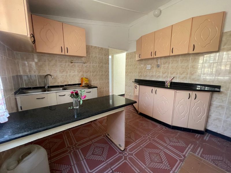 A functional kitchen featuring granite countertops, ample laminate cabinetry, and ceramic tile finishes throughout.