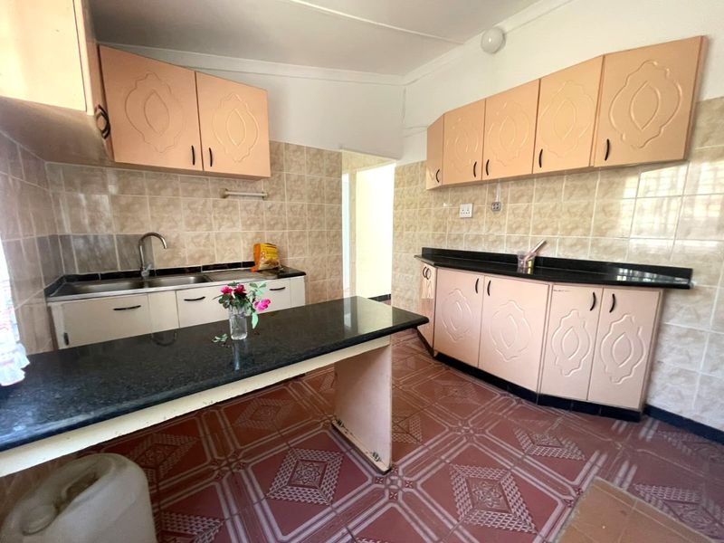 A functional kitchen featuring built-in cabinetry, granite countertops, and a double basin sink, finished with tiled backsplash and flooring.