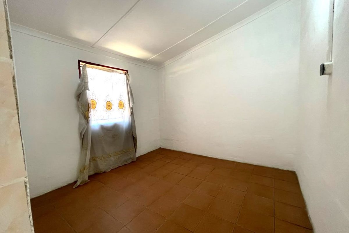 A vacant bedroom featuring terracotta-style floor tiles, white walls, and a coved ceiling, offering a blank canvas for renovation or interior design.