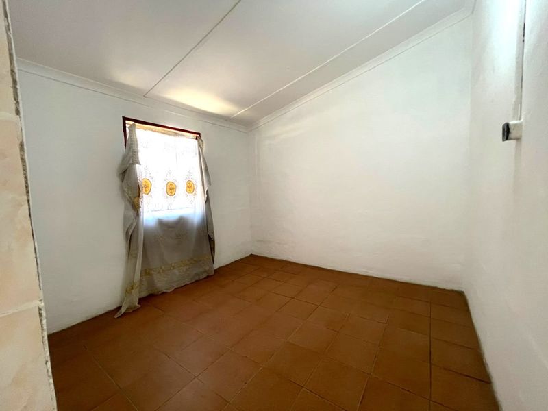 A vacant bedroom featuring terracotta-style floor tiles, white walls, and a coved ceiling, offering a blank canvas for renovation or interior design.