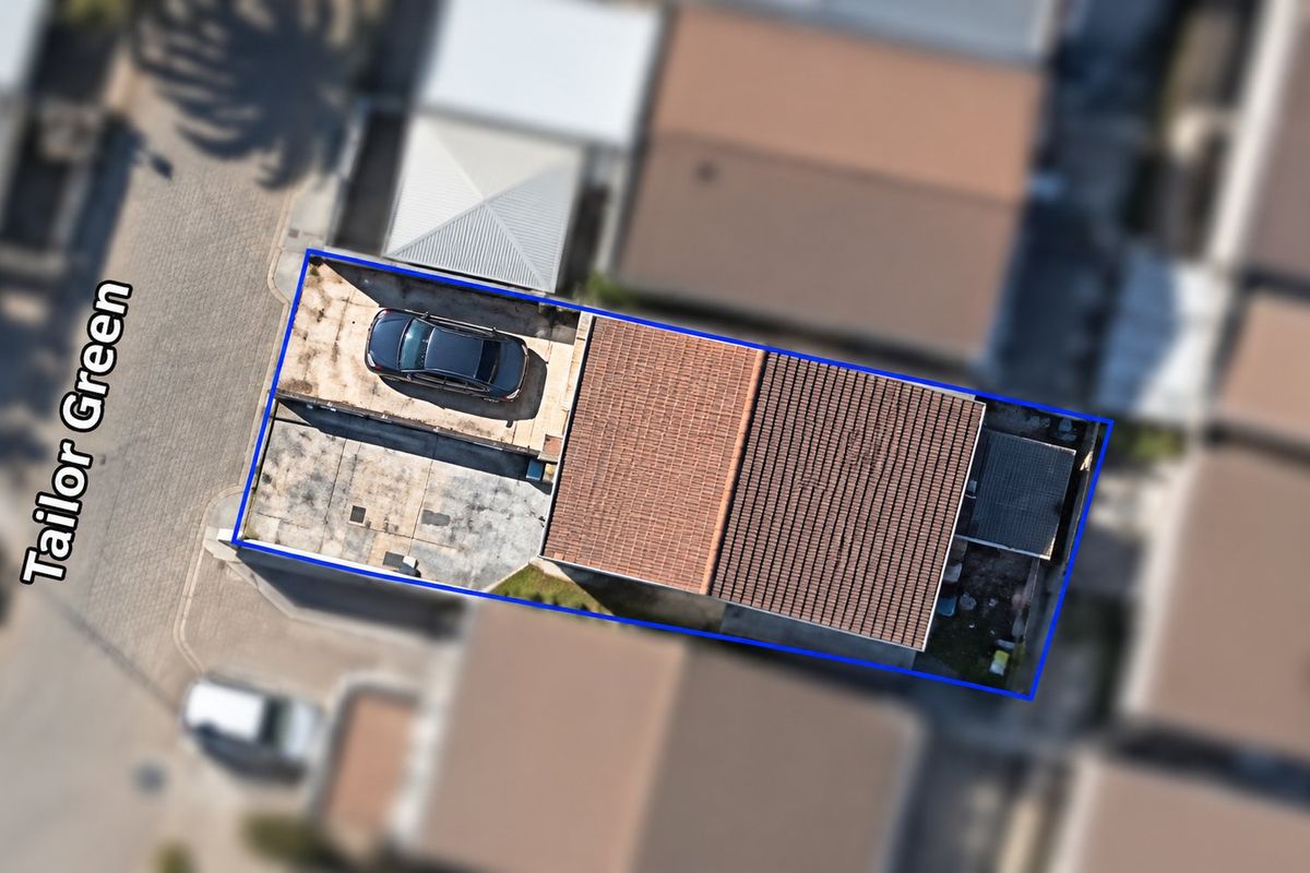 Aerial view of the townhouse property showing the roof structure, paved driveway, and surrounding site boundaries.