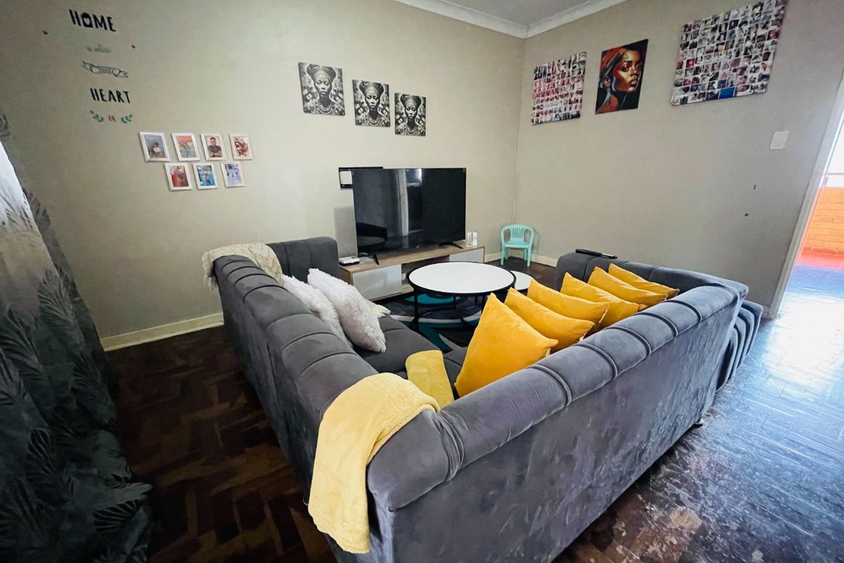 A living room featuring traditional parquet flooring and coved ceilings, offering a functional space with potential for cosmetic updates to enhance its appeal.