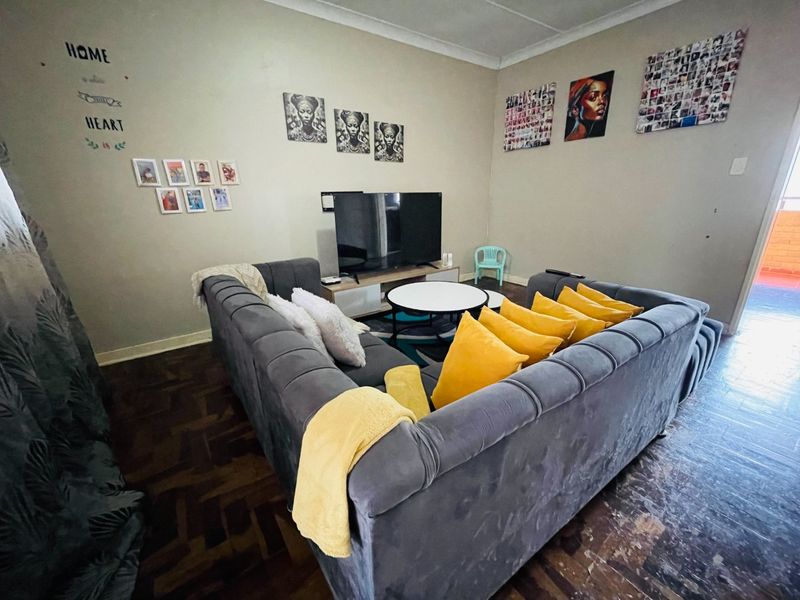 A living room featuring traditional parquet flooring and coved ceilings, offering a functional space with potential for cosmetic updates to enhance its appeal.