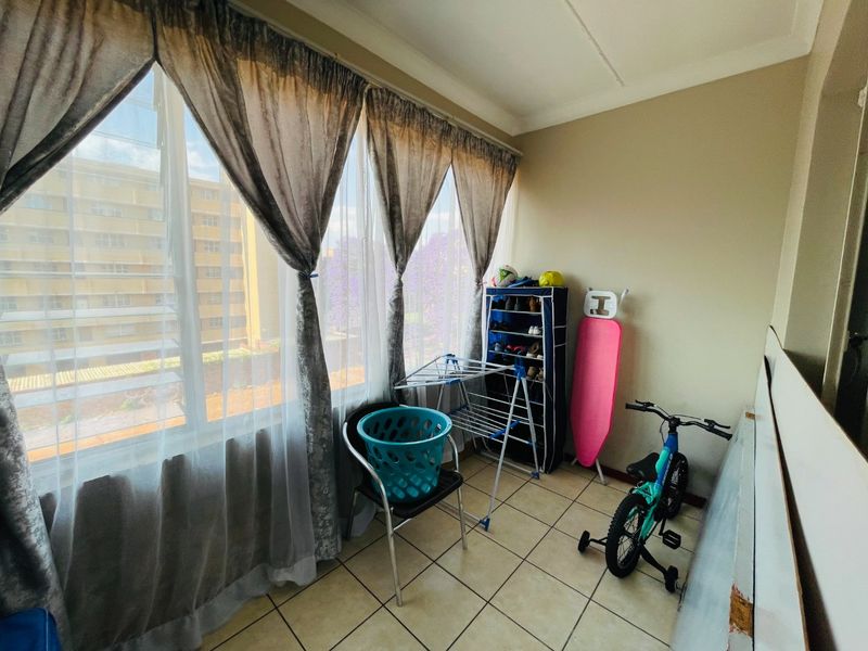 A functional enclosed balcony or sunroom featuring tiled flooring and large windows, offering a versatile space for storage or relaxation.