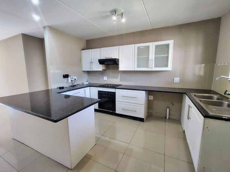 A functional kitchen featuring white cabinetry, dark granite countertops, a built-in oven with gas hob, and tiled flooring.