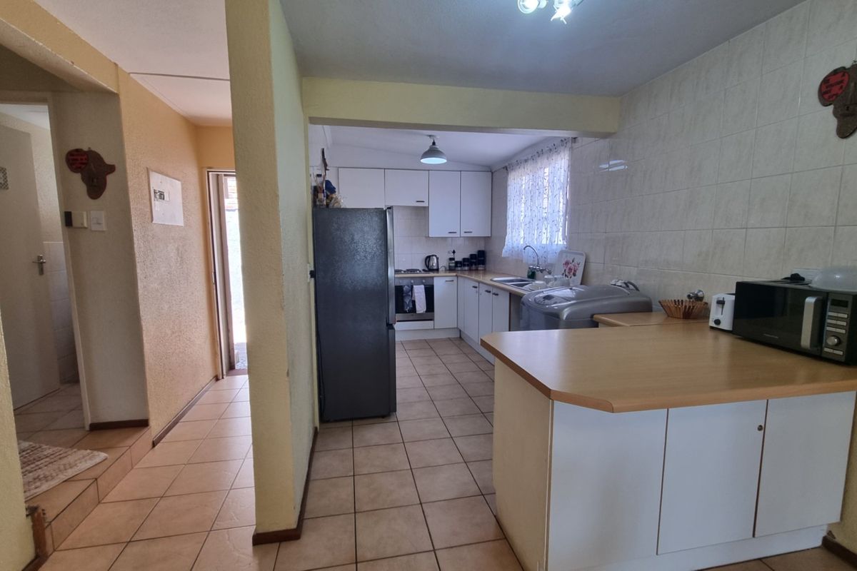 A functional kitchen featuring built-in cabinetry, laminate countertops, tiled backsplash, and tiled flooring, offering a practical layout for daily meal preparation.