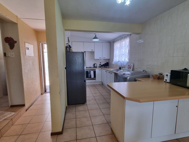 A functional kitchen featuring built-in cabinetry, laminate countertops, tiled backsplash, and tiled flooring, offering a practical layout for daily meal preparation.
