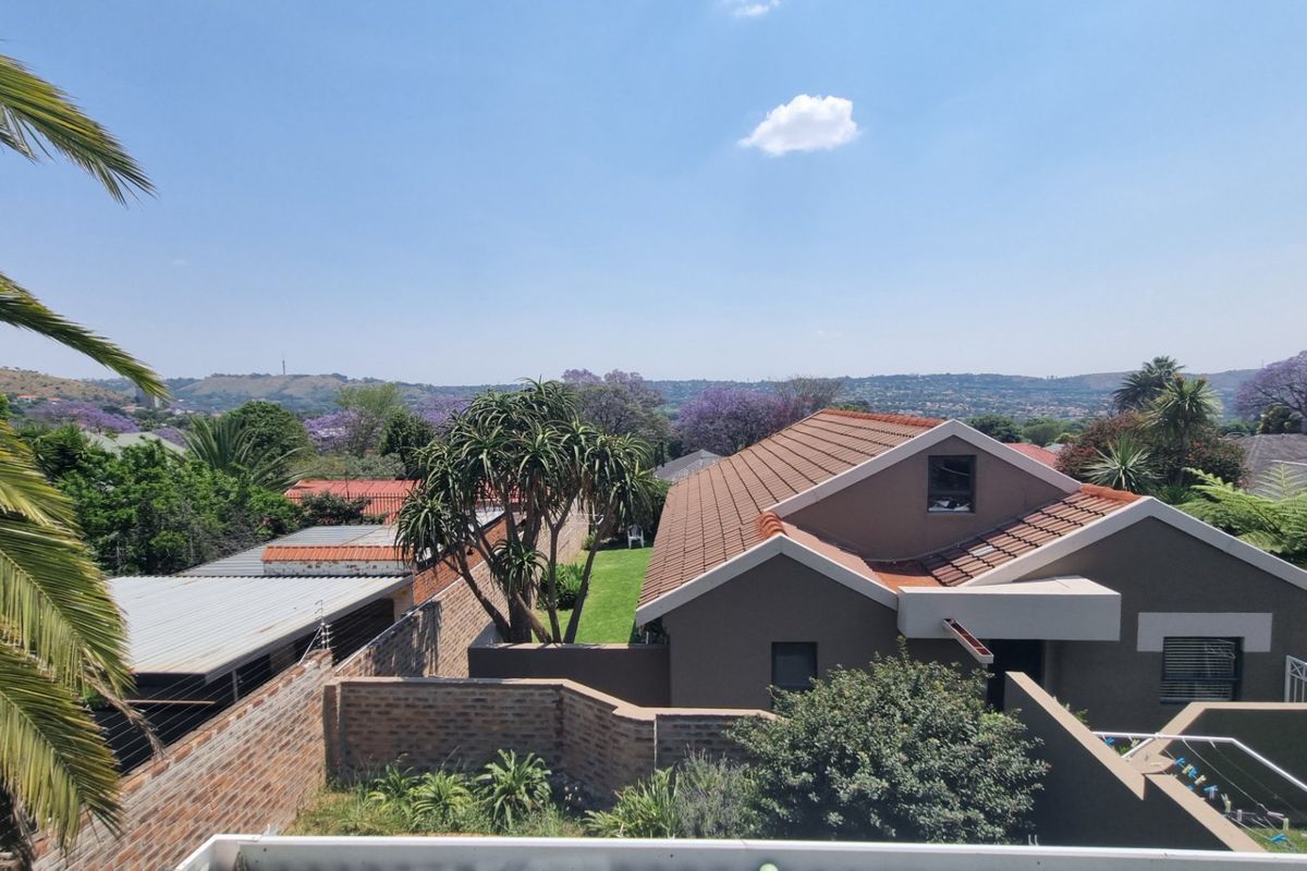 An elevated aerial view of the townhouse property, showcasing the tiled roof, surrounding garden, and established neighborhood landscape.